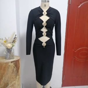 Détail d'une robe moulante noire avec découpes ajourées et anneaux métalliques dorés