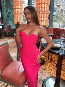 Detail of the sweetheart neckline on a fuchsia strapless dress worn by a model in a lounge