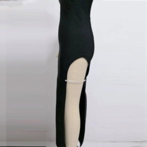 Detail of high side slit on black bodycon dress with sparkling rhinestone chain accent