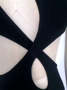 Dettaglio del tessuto a coste nero che mostra il taglio monospalla e lo stile bandage