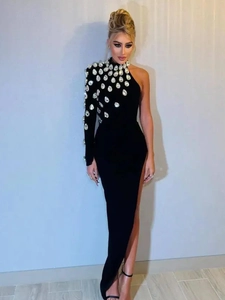 Detail of one-shoulder black evening dress featuring large teardrop crystals and high slit