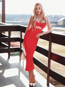 Sleeveless red bodycon party dress with bow detail and front cutout on a sunny balcony