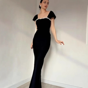Detail des eleganten eckigen Ausschnitts mit luxuriöser Strassverzierung am schwarzen Kleid