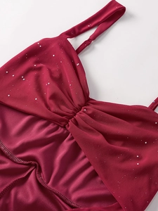 Detail of burgundy mesh dress featuring silver sequins, pleated bow chest, and slim straps