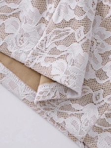 Gros plan sur la dentelle florale blanche avec doublure kaki et coutures fines sur la robe
