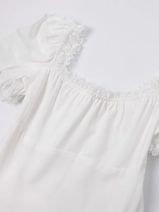 Detail of square neckline with lace trim and pleated puff sleeves on white dress
