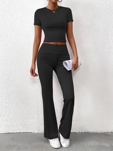 Détail d'un ensemble crop top noir ajusté et pantalon évasé taille haute en tissu extensible