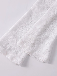 Gros plan sur les motifs floraux en dentelle blanche et la broderie sur les manches
