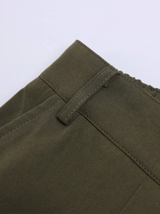 Détail du pantalon en coton olive foncé avec passants de ceinture renforcés et coutures fines
