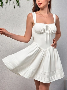 Detail of white A-line dress featuring a square neckline with pleated bust and tie knot