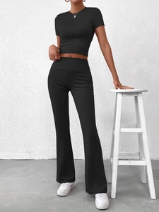 Détail d'un ensemble de yoga noir comprenant un crop top et un legging évasé moulant