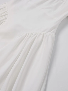 Detailed close-up of refined pleated fabric on white square neck dress with neat stitching