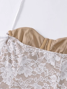 Détail du tissu en dentelle florale blanche avec coutures de soutien sur une robe licou
