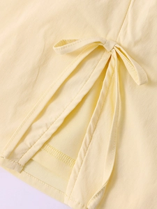 Détail du tissu en crêpe jaune avec un nœud décoratif et une fente sur la jupe