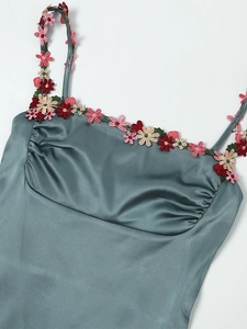 Détail de la robe en satin bleu-gris avec broderies florales et décolleté plissé élégant