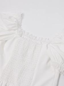 Detail of square neck dress featuring white smocking and delicate lace embroidery