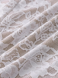 Gros plan sur la dentelle florale blanche et la maille nude aux détails raffinés