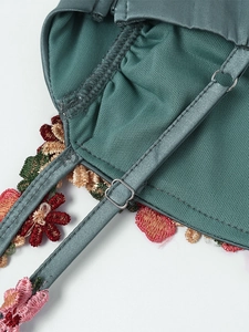 Détail de la robe en satin vert foncé avec broderie florale et boucle ajustable