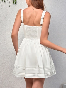 Detail of white mini dress featuring elastic smocked back and adjustable straps