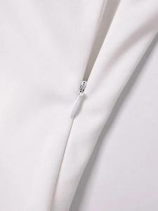 Detailed close-up of the seamless hidden zipper on a white halter neck bodycon dress