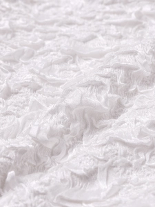 Close-up of white ruffled fabric with textured pleats on a French halter dress