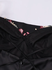 Dettaglio dell'abito in raso nero con ricamo floreale e scollo a V con spalline incrociate