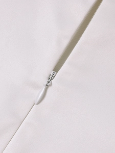 Detailed macro view of high-quality invisible teardrop zipper on white knit summer dress