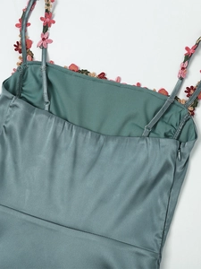 Vue détaillée de la robe en satin vert sauge avec broderie florale et bretelles