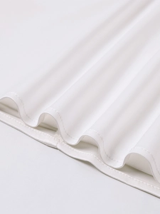 Detailed macro view showing the clean hem stitching of a white knitted mini dress