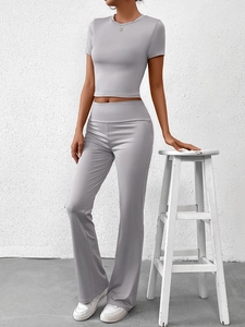 Détail du pantalon évasé gris clair taille haute et t-shirt court avec coupe ajustée