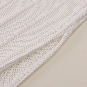 Close-up of white knitted summer dress showing hollow crochet patterns and mesh texture