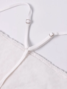Dettaglio di spalline regolabili e bordo in pizzo su un set tubino bianco in mesh patchwork