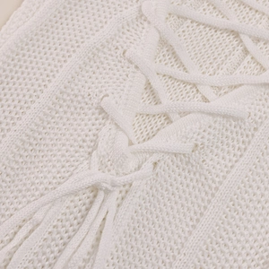 Detailed view of white knit dress featuring intricate lace-up ties and hollow mesh texture