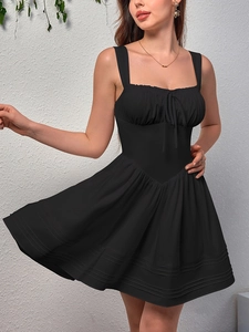 Close-up of black sleeveless dress featuring pleated bust with bow and tiered flared skirt