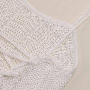 Detail of white crochet knit top with thin straps and lace-up texture for summer