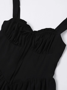 Close-up of black summer dress with ruffled neckline and delicate bow detail