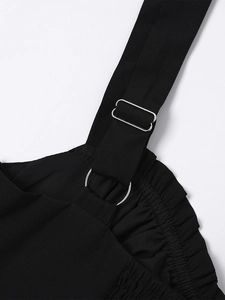 Detail of adjustable silver buckles and metal rings on black strap dress with ruffles