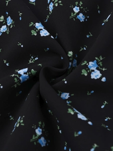 Vue macro détaillée du tissu floral noir avec petites fleurs bleues et feuilles vertes