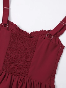 Detail of adjustable straps and elastic smocked back on a dark red summer dress