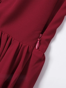 Detail of burgundy dress featuring a concealed zipper and pleated woven fabric texture