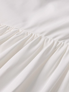 Detail of white summer dress showing intricate pleats and high-quality sewing craftsmanship