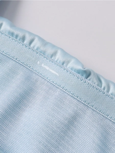Détail du tissu élastique bleu clair montrant les plis élastiques et la couture à double aiguille