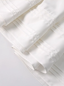 Detail of white summer dress showing horizontal tucking pleats and fine cotton texture