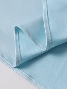 Gros plan d'une robe bleu clair montrant les coutures fines et la bordure en satin