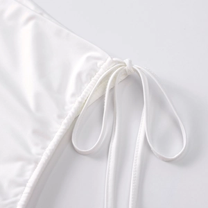 Detail of white milk silk fabric with side drawstring and fine stitching on the mini skirt