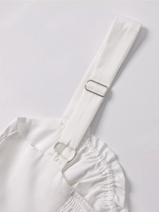 Detail of white strap dress with silver metal rings and adjustable buckles on pleated fabric