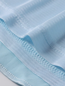 Détail macro des coutures du tissu bleu clair et du contraste avec le fini satiné