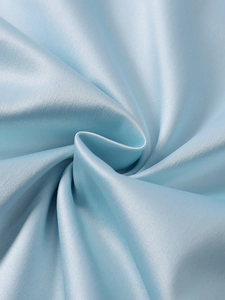 Gros plan sur un tissu élastique mat bleu clair avec texture soyeuse et drapé élégant