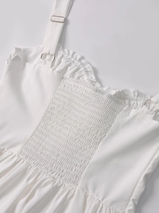 Detail of white mini dress featuring smocked elastic back and adjustable thin straps