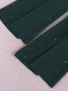 Détail du tissu en maille vert foncé avec paillettes argentées et sequins arc-en-ciel